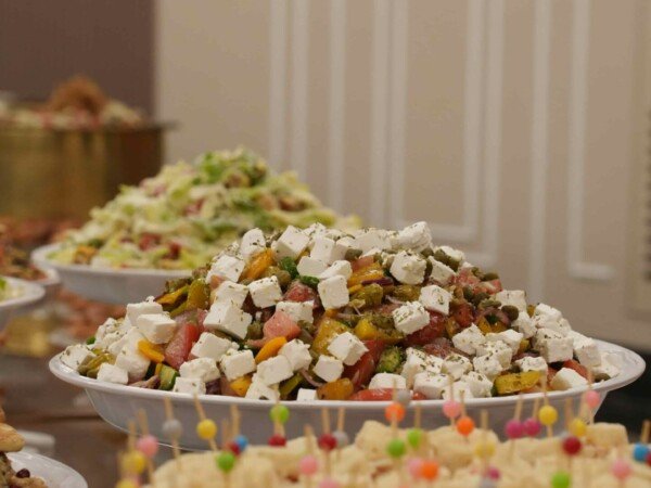 Indoor catering buffet with bite-sized sandwiches and salad bowls arranged on serving trays for an event.